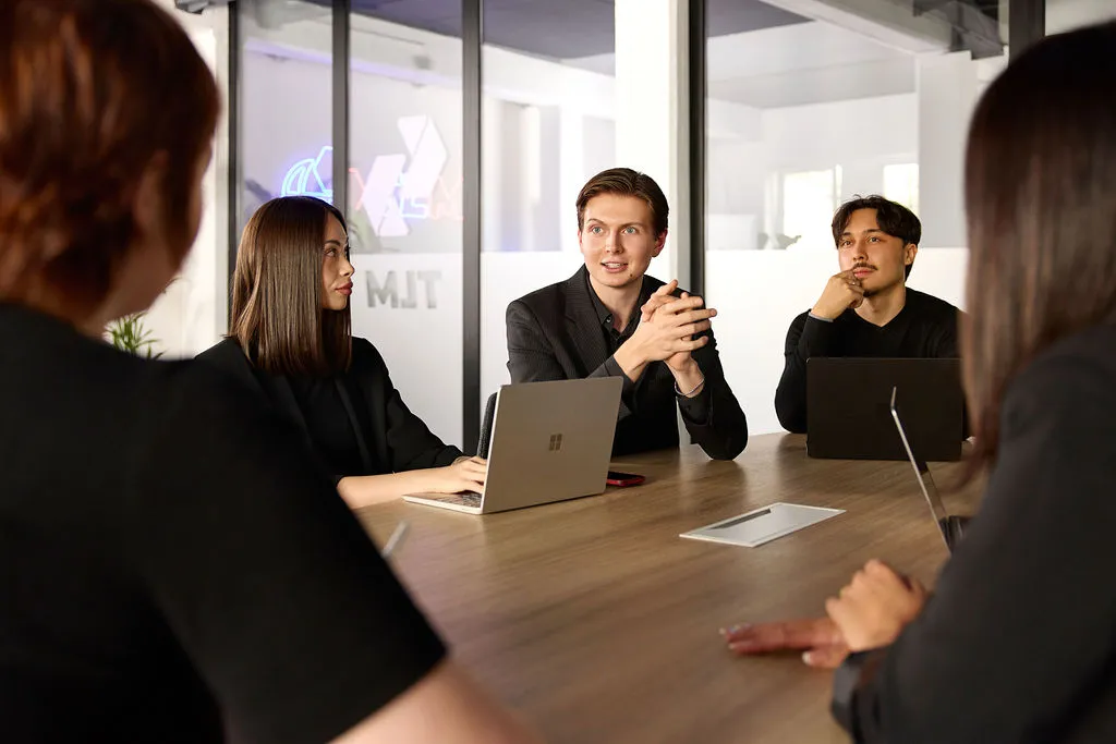 Besprechung am Konferenztisch, ein Kollege erklärt, die anderen hören zu
