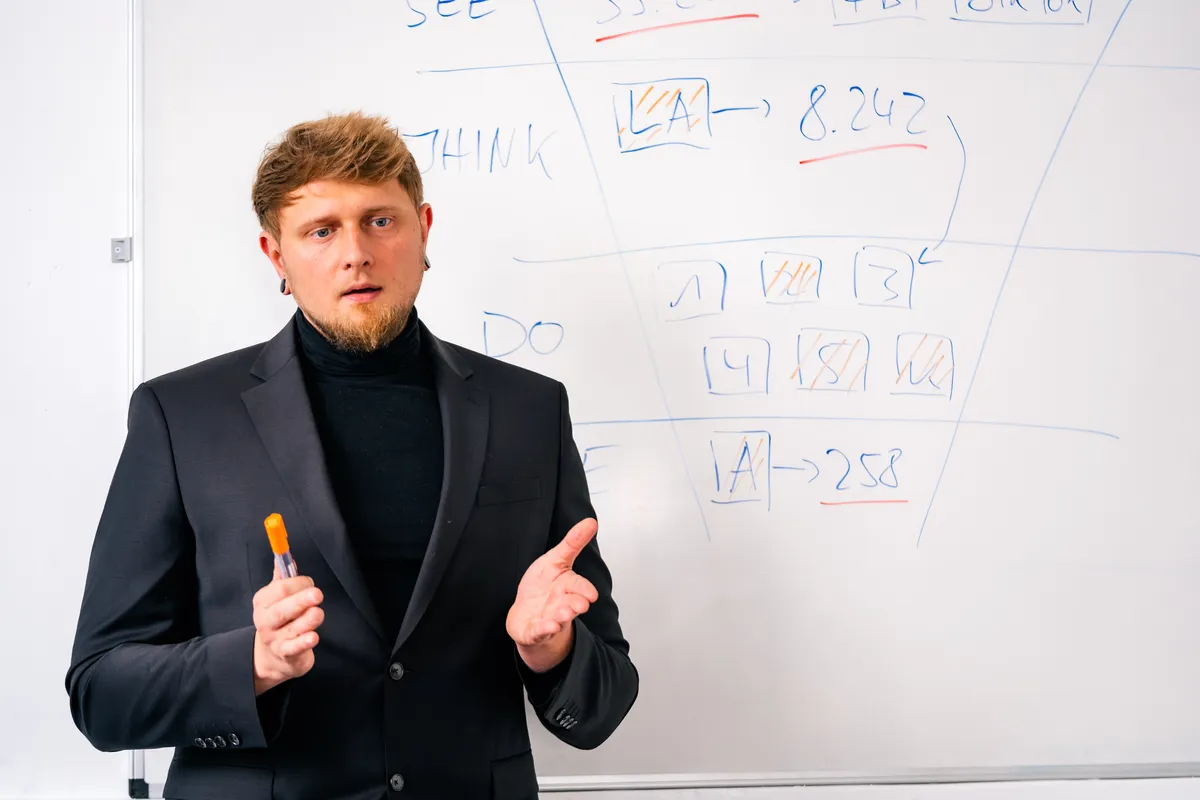 Ein Kollege erklärt am Whiteboard Zahlen aus einer Kampagne